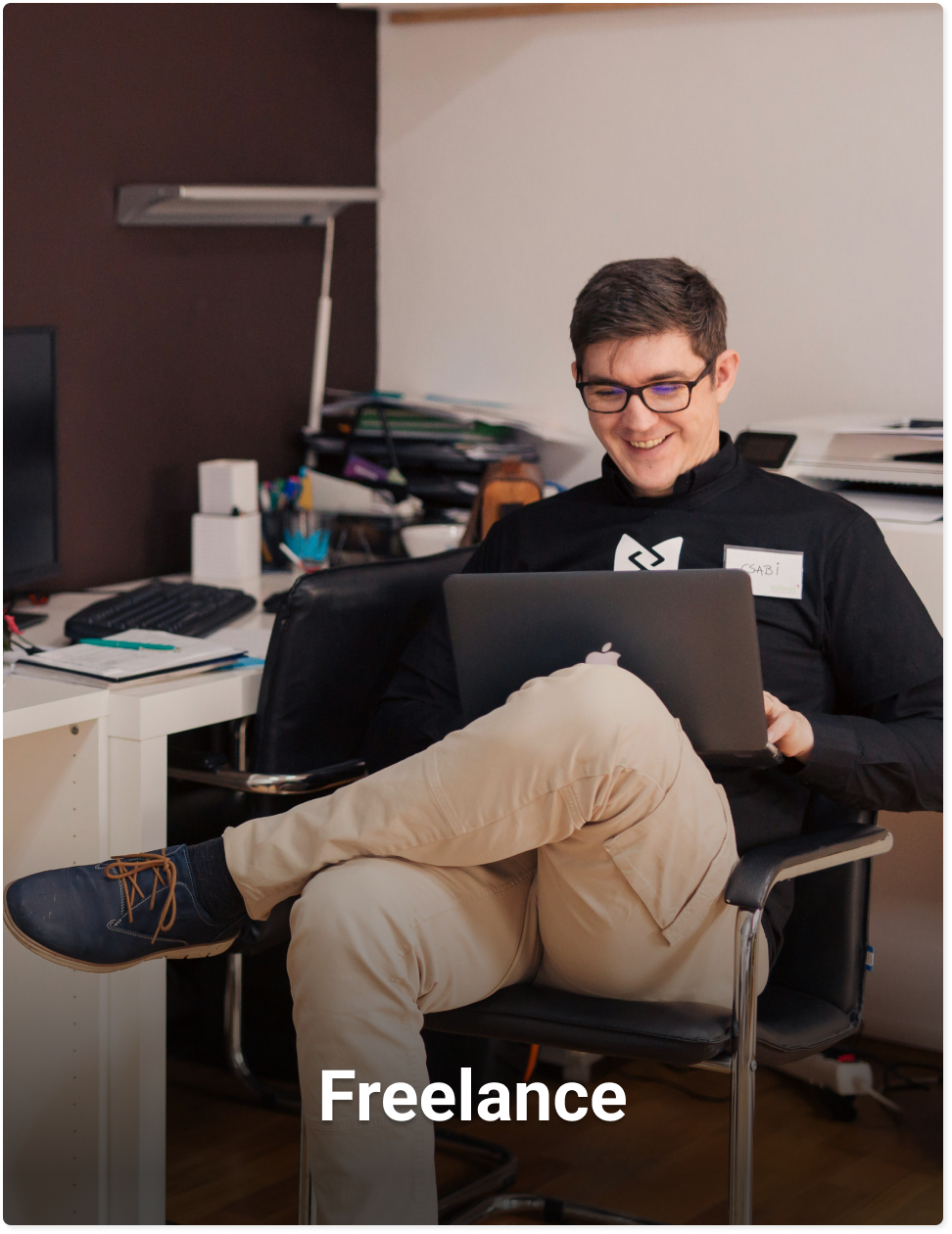 Lachende man op een stoel achter een laptop