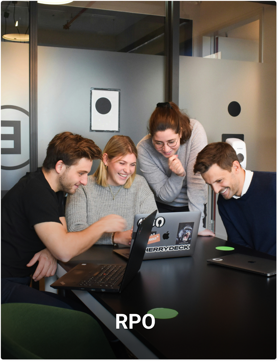 Vier mensen, twee mannen en twee vrouwen lachen en kijken naar 1 laptop